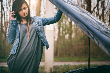 Woman with brown hair under the hood of her car break down