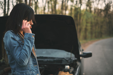 Woman with brown hair under the hood of her car break down