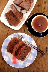 Homemade chocolate cake cut with pink candies and tea in blue cu
