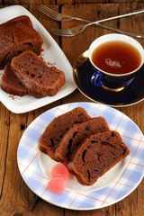 Homemade chocolate cake cut with pink candies and tea in blue cu