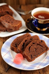 Homemade chocolate cake cut with pink candies and tea in blue cu