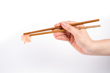 Hand holding sushi ginger with bamboo chopsticks isolated on whi