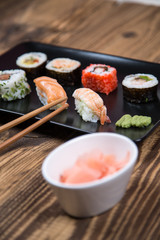 Sushi pieces collection with bamboo chopsticks, isolated on wooden table