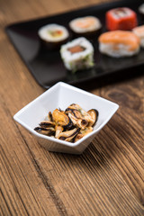 Sushi pieces collection with bamboo chopsticks, isolated on wooden table