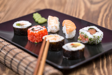 fresh Japanese tasty sushi roll set with chopsticks on wooden ta