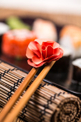 Obraz na płótnie Canvas Sushi chopsticks with origami flower on sushi background