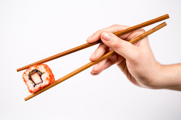 Hand holding Sushi roll with bamboo chopsticks isolated on white