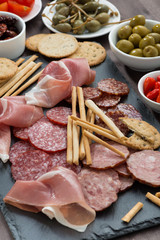 Assorted meat snacks, sausages and pickles on a blackboard