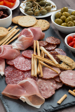 Assorted meat snacks, sausages and pickles on a blackboard
