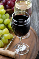 glass of red and white wine, corkscrew and grapes