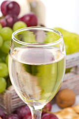 glass of white wine and grapes in the background, close-up