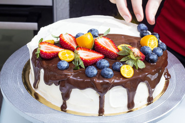 woman decorates berry cake with blueberry