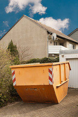 Fototapeta na wymiar Ein grosser oranger Container steht in einer Garagenauffahrt