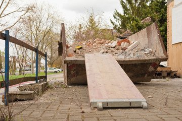 Ein teilweise mit Bauschutt gefüllter Container mit Rampe