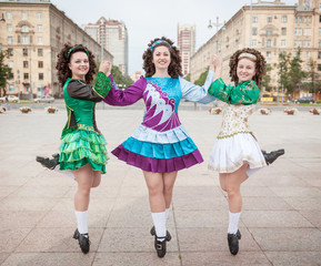 Three women in irish dance dresses and wig posing