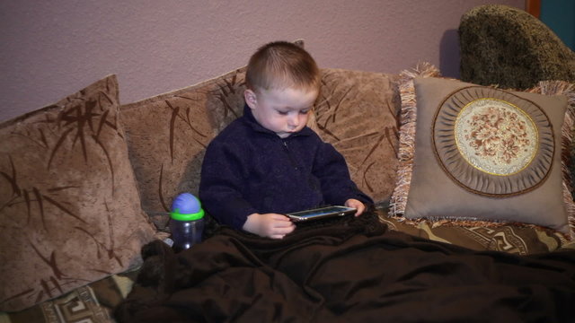 Little boy sitting on the couch and watching a cartoon