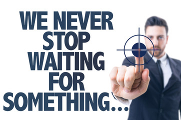 Business man point: We Never Stop Waiting For Something... - obrazy, fototapety, plakaty