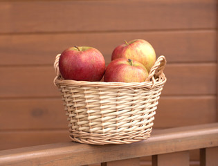 Ripe red and yellow apples in light brown wicker basket