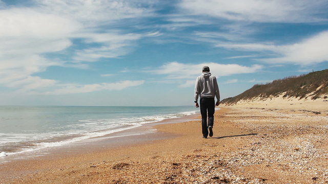 happy man going along the beach in sunny spring day