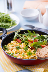 Scrambled eggs with fresh salad in frying pan