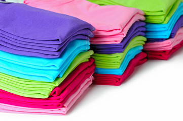 Piles of multi-colored women's t-shirts on white background