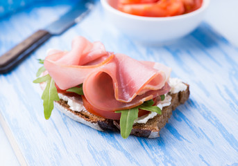 Open sandwiches with ham, tomato and arugula