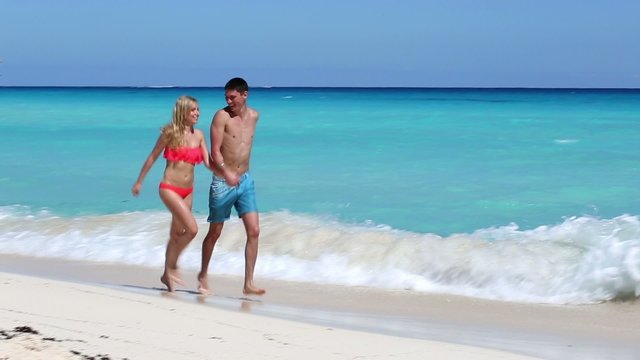 Young couple running  on caribbean beach