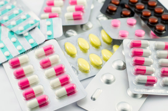 Capsules and pills packed on white background