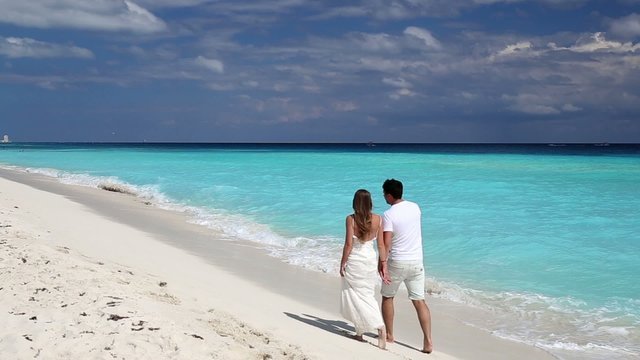 Young beautiful newlyweds on white sandy beach
