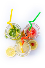 Different tips of lemonade in the jug with straws