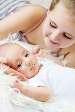 cute little sister looks at newborn