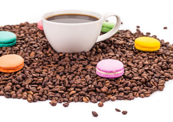Cup of coffee on beans with macarons.