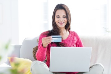 Smiling beautiful brunette doing online shopping on the couch