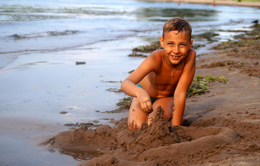 Fototapeta na wymiar Загорелый мальчик играет на пляже