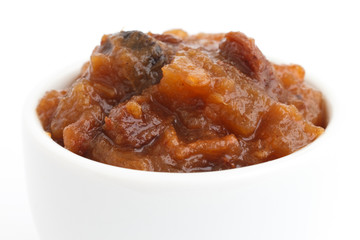 Detail of rough fruit chutney in white dish.