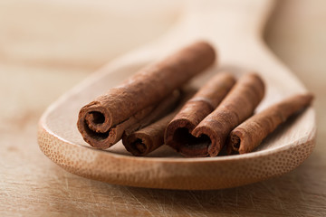 whole cinnamon sticks in spoon on wooden background