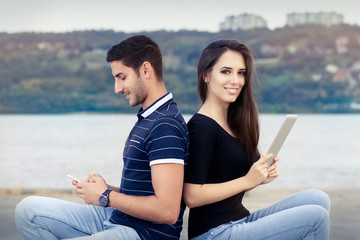 Happy Couple Checking their Smartphone and Tablet