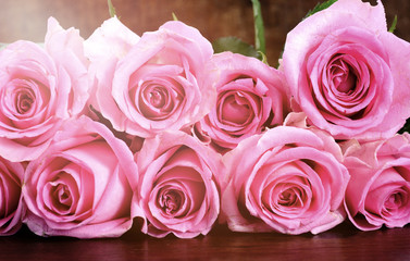Vintage style pink roses on rustic dark wood table. © millefloreimages
