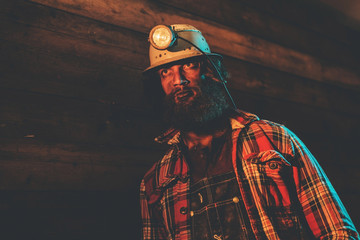 Miner Wearing Helmet Lamp Leaning Against Wall