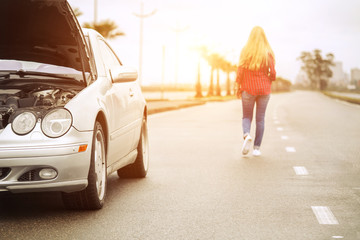 Upset blonde woman leaving her broken roadster