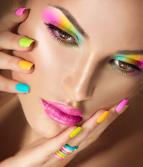 Beauty girl face with vivid makeup and colorful nail polish