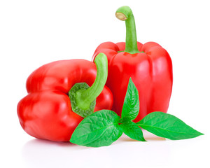 Two Sweet Red Peppers with green leaves isolated on white backgr