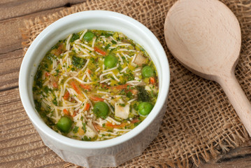 Soup with pasta and vegetables on old wooden table