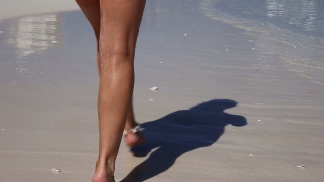 Beautiful woman legs, walking along the beach
