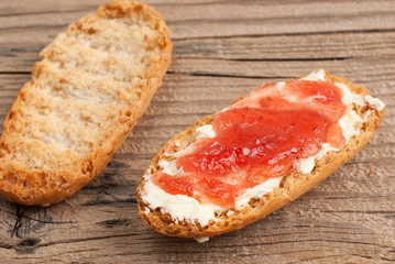 Rusk with butter and jam on old wooden table