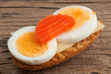 Rusk sandwich with egg and carrot on old wooden table