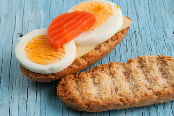Rusk sandwich with egg and carrot on old wooden table