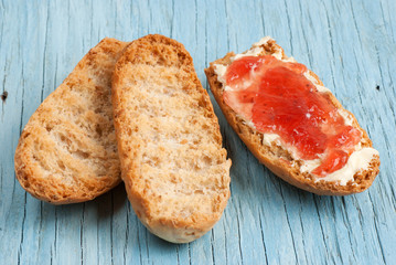 Rusk with butter and jam on old wooden table
