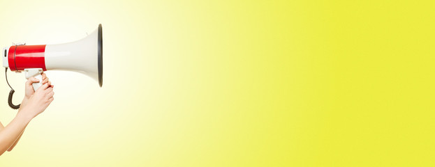 Hand hält Megafon vor Hintergrund in gelb