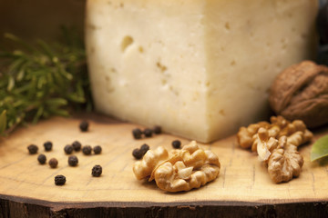 Organic walnuts and hard cheese on wooden board